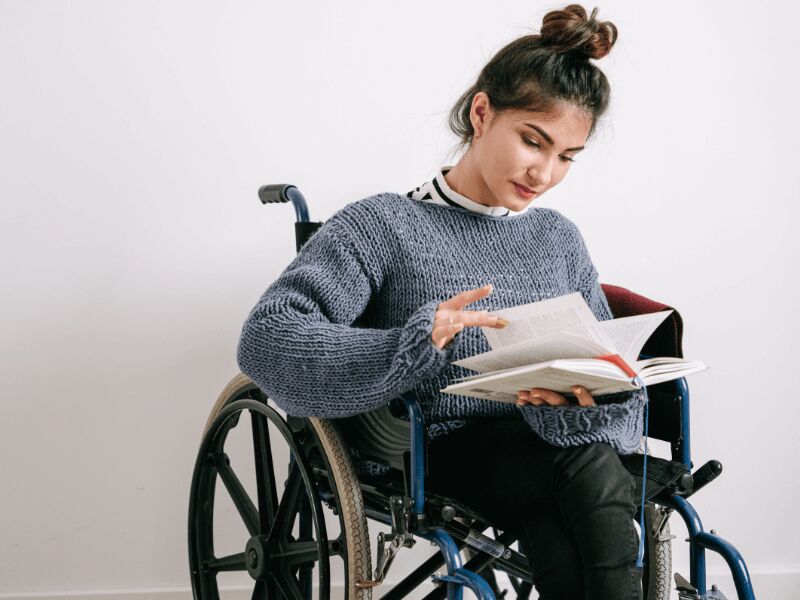 Frau im Rollstuhl liest als Beispiel für Assistenz am Arbeitsplatz