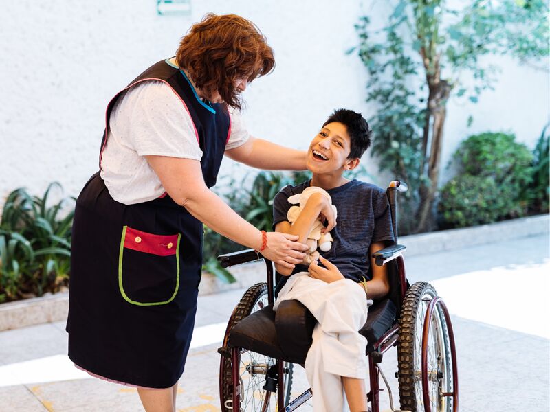Ein Foto von einer Frau, die mit einem Kind im Rollstuhl spricht.